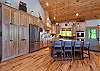 Chef's kitchen with wood cabinetry, stainless appliances, gas cooktop, and island seating.