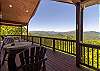 Spacious deck with rustic barrel table and log chair seating overlooking the mountains.