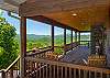 Wraparound deck with rocking chairs and panoramic mountain views.