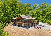 Welcome to Above and Beyond. Aerial view of the cabin's front with gabled roofline, chimney, deck, and fire pit circle.