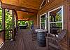 Covered main deck with barrel table seating and a view of the hot tub down the deck.