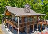 Aerial view of the cabin's two-level deck system and stacked stone chimney.