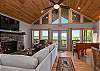 Elegant living area with a stacked stone gas fireplace, grand piano, and deck access.