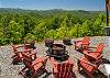 Fire pit surrounded by chairs and flower barrel planters with mountain views.
