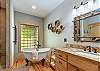 Primary bath with a clawfoot soaking tub, vanity, and walk-in tiled shower.