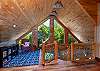 Vaulted wood-ceiling loft with floor-to-ceiling A-frame windows and a reading nook.