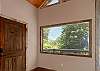 Bright foyer with vaulted wood ceiling and a wide view of the tree line.