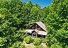 Close drone view of the cabin's exterior and deck tucked into the trees.
