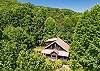 Drone shot highlighting the cabin's A-frame design and covered deck.