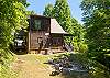 Open backyard with a stone fire pit, seating, hammock, and wooded privacy on all sides.