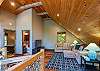 Open loft with sectional sofa, flat-screen TV, wood ceiling, and access to bedroom and bath.