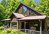 Full view of the cabin's front featuring large picture windows, covered porch, and chairs.